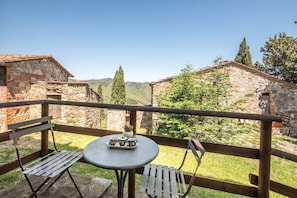 A balcony with a table and chairs, overlooking a mountainous landscape.