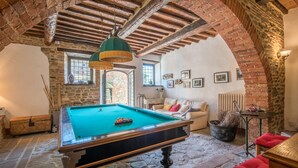 A billiards table in a room with stone walls, a wooden ceiling, and a cozy seating area. - Casale Rosennano Apartment – Shared Garden, Wi-Fi, Medieval Setting (Rosennano)