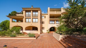 Un edificio de varios pisos con un patio empedrado, balcones y una escalera que conduce a la entrada.