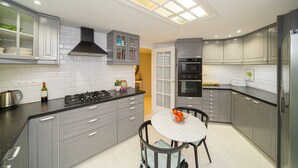 Una cocina moderna con armarios grises, una estufa negra y una mesa de comedor redonda con sillas.