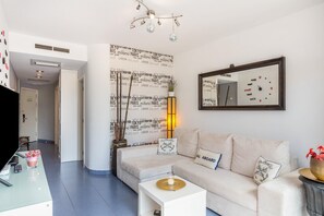 Un salon moderne comprenant un canapé, une table basse, un téléviseur et des objets de décoration.