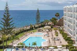 A resort with a large pool, sun loungers, and a view of the sea. - Apartment 'Riviera Peace' close to the Beach with Shared Pool & Wi-Fi (Mogán)