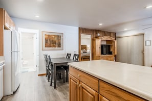 A modern kitchen with wooden cabinets, a dining table with chairs, a refrigerator, and a television. - Hidden Valley Village #103 nicely updated 1 bedroom 1 bathroom condo short 10 min walk from Village (Mammoth Lakes)