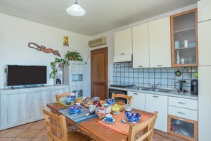 Une cuisine équipée d’une table à manger dressée pour le repas, d’un téléviseur et de placards.