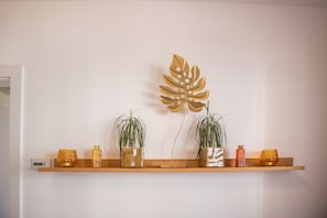 A shelf with decorative items and plants against a plain wall.