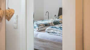 Et soveværelse med en seng, en senget lampe og en lyskontakt på væggen.