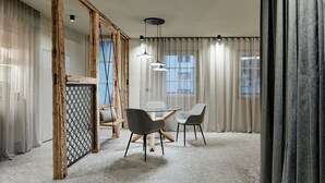 Une pièce moderne avec une table en verre, deux chaises, des poutres en bois et un luminaire suspendu.
