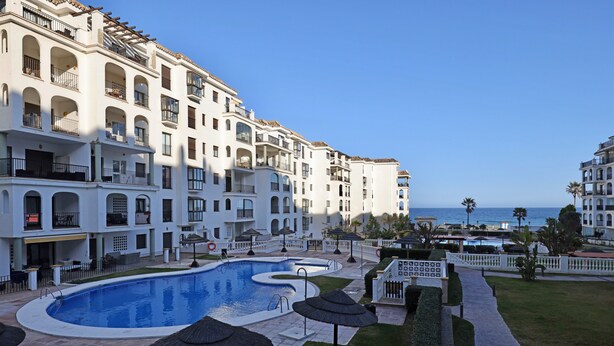 Un hotel con piscina, sombrillas exteriores y vista al mar.