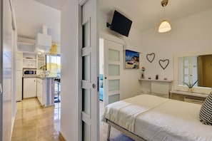 Ett modernt hotellrum med en säng, en TV, ett skrivbord och ett badrum.