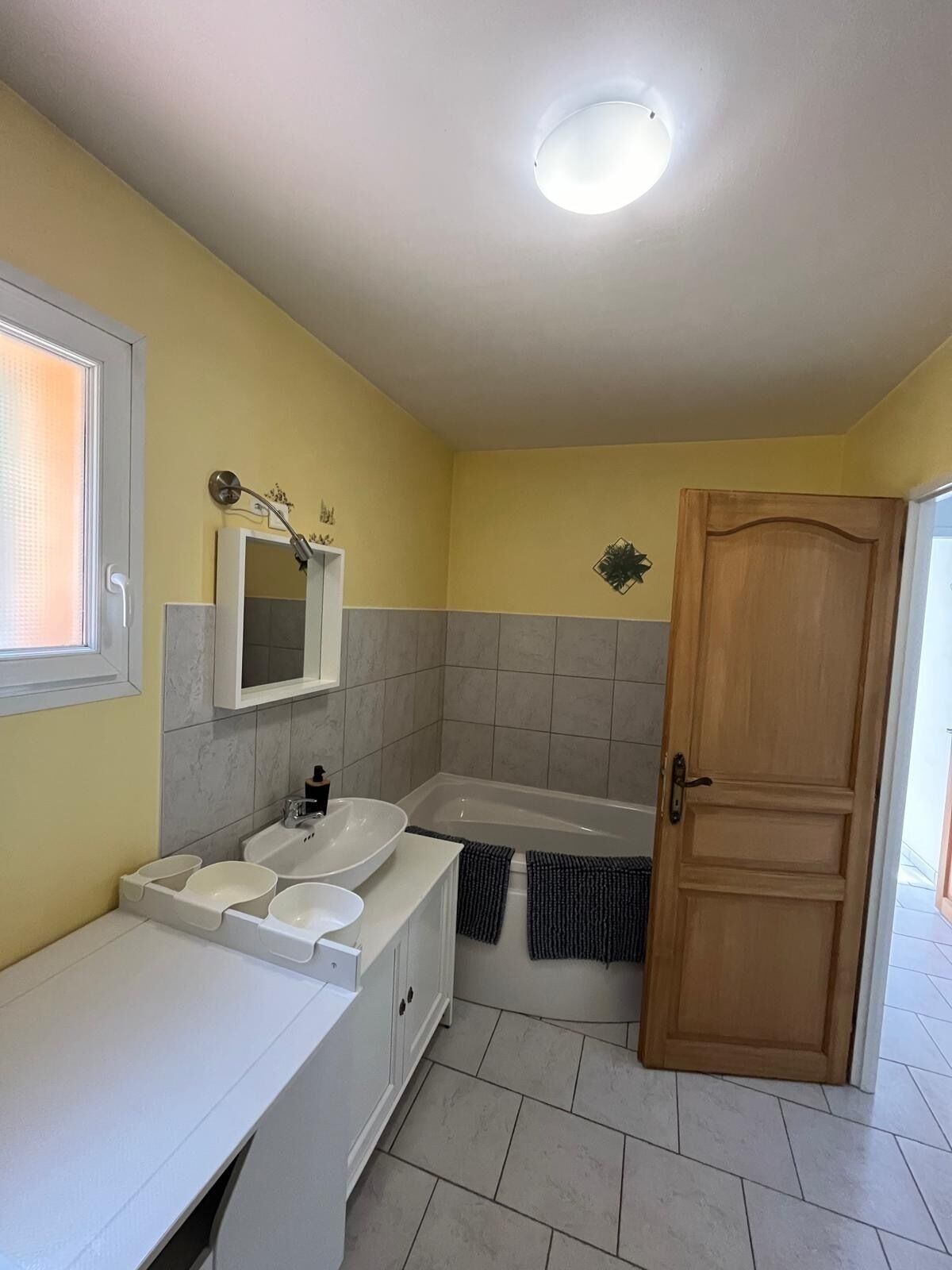 Un baño con lavamanos, espejo y bañera blancos.