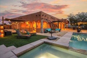 A modern house with a swimming pool, outdoor seating, and string lights. - Luxury 4BR Joshua Tree House w/ heated Pool (Yucca Valley)