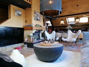 A cozy living room with a fireplace, wooden walls, and a modern black coffee table.