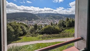 A view from a window overlooking a town with a mountainous backdrop.