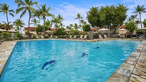 A swimming pool with clear blue water, surrounded by palm trees and lounge chairs. - 🏖️Oceanfront Penthouse w/ AC + Pickleball + Views (Kailua Kona)