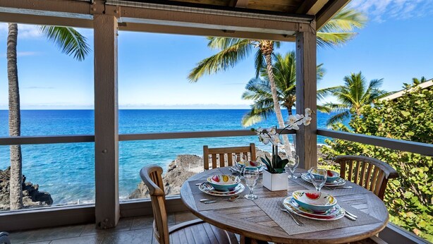 A table set for dining with a view of the ocean and palm trees. - 🏖️Oceanfront Penthouse w/ AC + Pickleball + Views (Kailua Kona)
