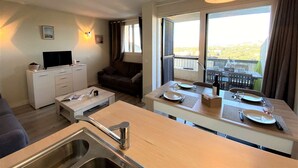 A compact living space with a kitchenette, a dining area, and a seating area with a view.