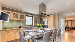 A modern kitchen with a central island, built-in appliances, and a large window.