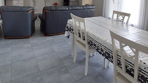 Ein geräumiger Wohnbereich mit Esstisch, zwei Sofas, Fernseher und Kamin.