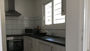 Eine moderne Küche mit eingebautem Backofen, Mikrowelle und Dunstabzugshaube aus Edelstahl.