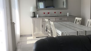Eine moderne Küche mit weißen Schränken, einem Esstisch und Stühlen. Über dem Tisch hängt eine Deckenleuchte.