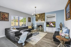 A modern living room with a fireplace, a television, and a comfortable seating area. - Terra Azul: Pool, Spa, Billiard Table, Foosball (Indio)