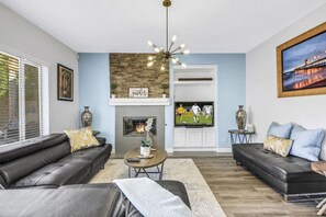 A living room with a fireplace, a television, and two sofas. - Terra Azul: Pool, Spa, Billiard Table, Foosball (Indio)