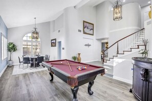 A spacious room with a pool table, a dining area, and a staircase leading to an upper level. - Terra Azul: Pool, Spa, Billiard Table, Foosball (Indio)