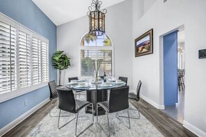 A dining area with a round table, chairs, and a chandelier. - Terra Azul: Pool, Spa, Billiard Table, Foosball (Indio)