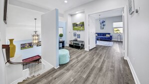 A spacious hallway with a billiards table, a blue sofa, and a television mounted on the wall. - Terra Azul: Pool, Spa, Billiard Table, Foosball (Indio)