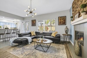 A modern living room with a sectional sofa, a round coffee table, and a fireplace. - Terra Azul: Pool, Spa, Billiard Table, Foosball (Indio)