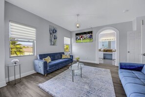 A modern living room with a blue sofa, a round coffee table, and a large TV screen. - Terra Azul: Pool, Spa, Billiard Table, Foosball (Indio)