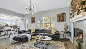 A modern living room with a sectional sofa, a round coffee table, and a fireplace. - Terra Azul: Pool, Spa, Billiard Table, Foosball (Indio)