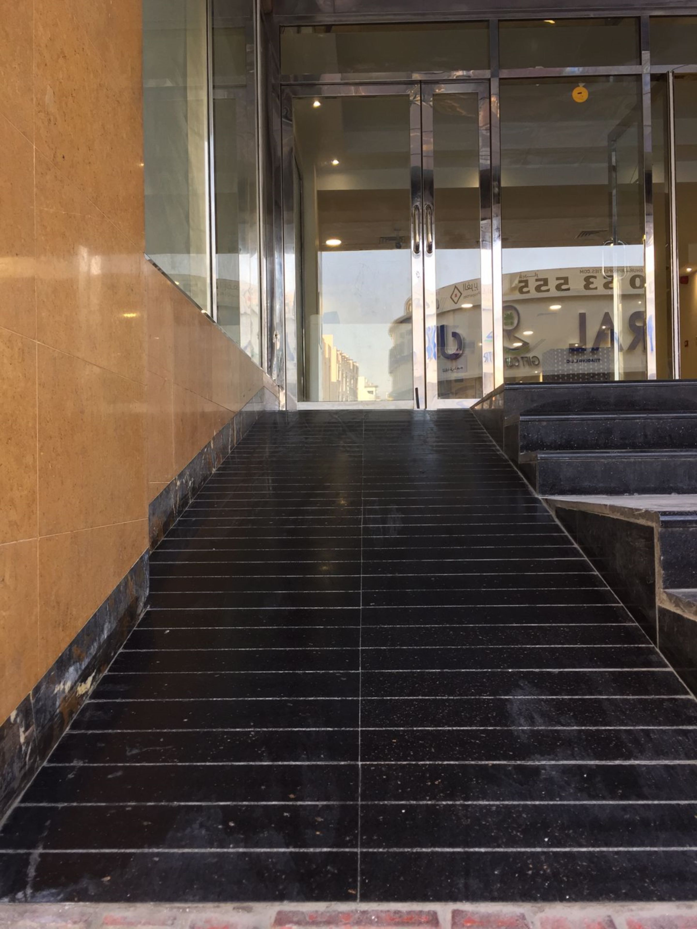 A set of black marble stairs leading to a glass door entrance.