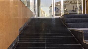 A set of black marble stairs leading to a glass door entrance.