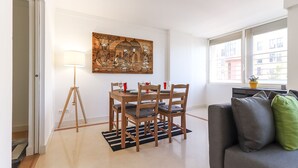 A dining area with a wooden table and chairs, a floor lamp, and a painting on the wall. - Lisbon Flower 360º - Your Lovely Flat with Pool and Parking (Lisboa)