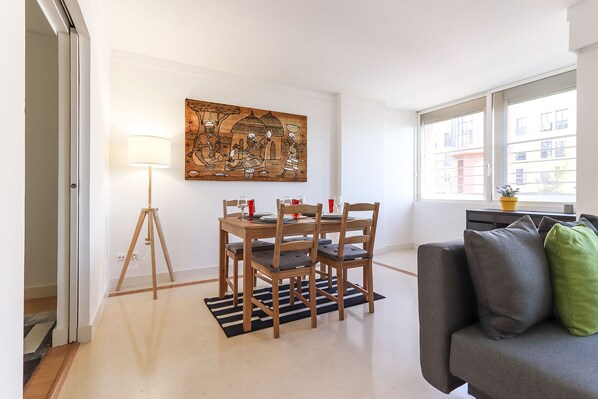 Un comedor con una mesa y sillas de madera, una lámpara de pie y un cuadro en la pared.