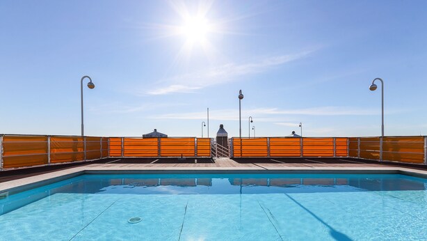 A swimming pool with a clear blue sky and sun in the background. - Lisbon Flower 360º - Your Lovely Flat with Pool and Parking (Lisboa)