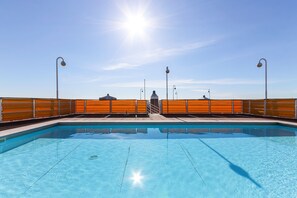 Una piscina con cielo azul despejado y sol de fondo.
