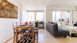 A modern living room with a dining area, a sofa, and a bookshelf. - Lisbon Flower 360º - Your Lovely Flat with Pool and Parking (Lisboa)