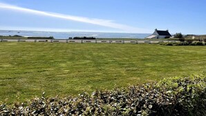 Een grasveld met een gebouw en uitzicht op zee.