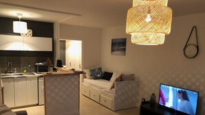 Een moderne woonkamer met een bank, een televisie en een keukenhoek.