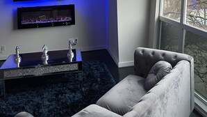 A modern living room with a flat-screen TV mounted on a wall, a decorative console table with two vases, and a grey sofa.