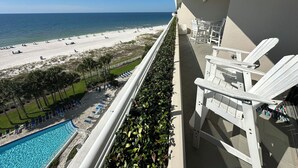 A balcony with white chairs and a view of a beach and pool. - Gulf Front Condo with Stunning Views! (Pensacola)