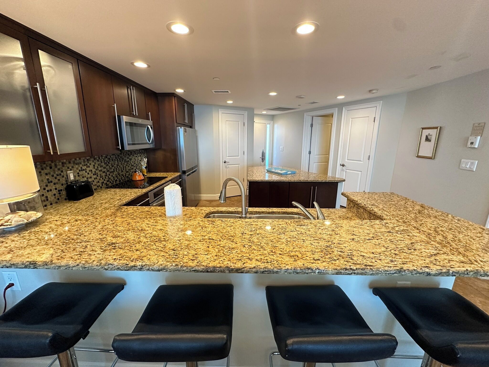 A modern kitchen with granite countertops, stainless steel appliances, and a central island with a sink.