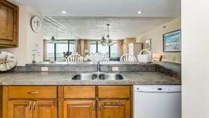 A kitchen with wooden cabinets, a double sink, and a dishwasher. - Gulf Front Condo with Stunning Views! (Pensacola)