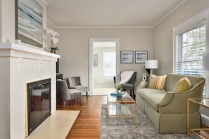 A living room with a fireplace, a sofa, armchairs, and a coffee table. - Luxurious Cape Cod in Emerywood - Minutes to Furniture Market & HP University (High Point)