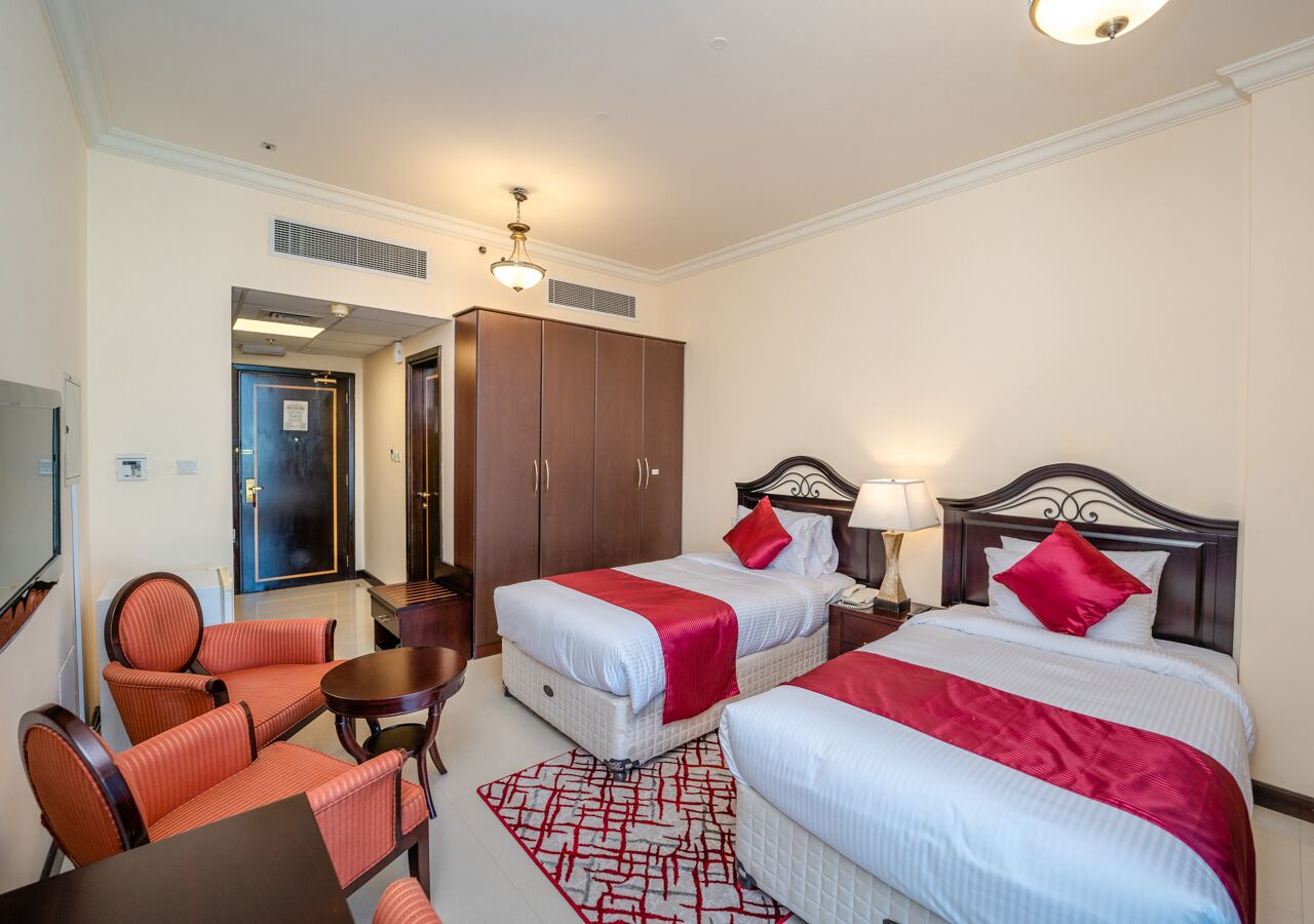 Ein Hotelzimmer mit zwei Betten, einem Schreibtisch, einem Stuhl und einem Fernseher.