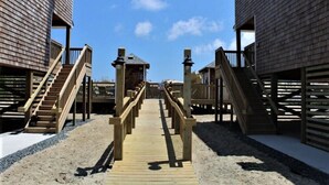 A wooden boardwalk leading to two buildings with balconies and staircases.