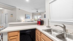 A modern kitchen with a dishwasher, a coffee maker, and a sink. - Salty But Sweet at Sundune Village, Located 0.1 Miles from the Beach! (Kill Devil Hills)