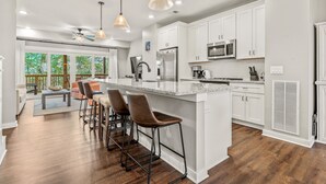 A modern kitchen with white cabinets, stainless steel appliances, and a large island with bar stools.